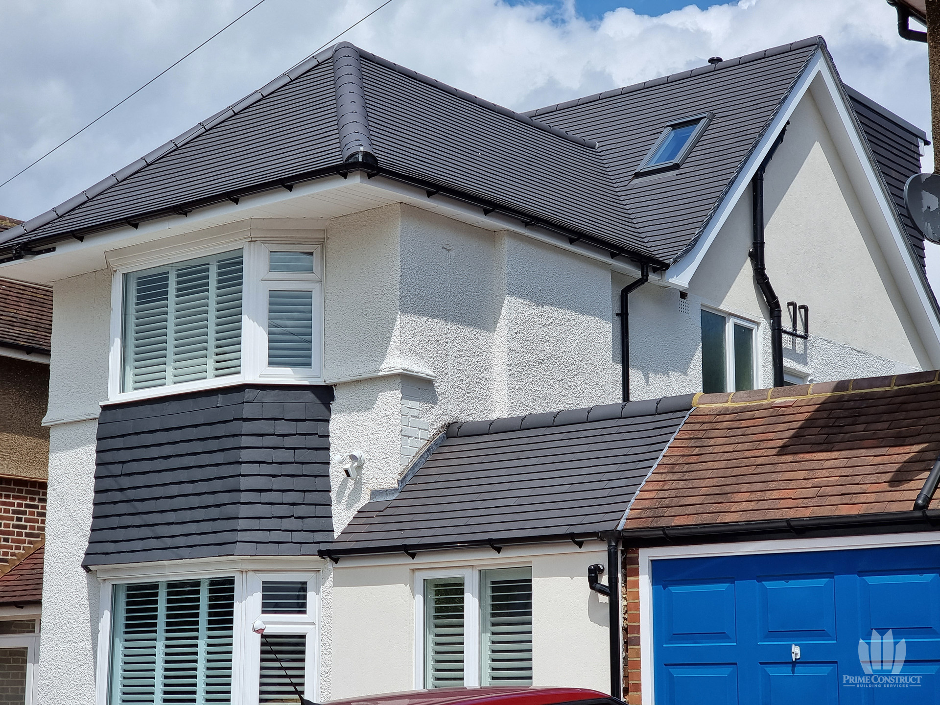 Upper front elevation with pale render, dark roof covering and a projecting bay.