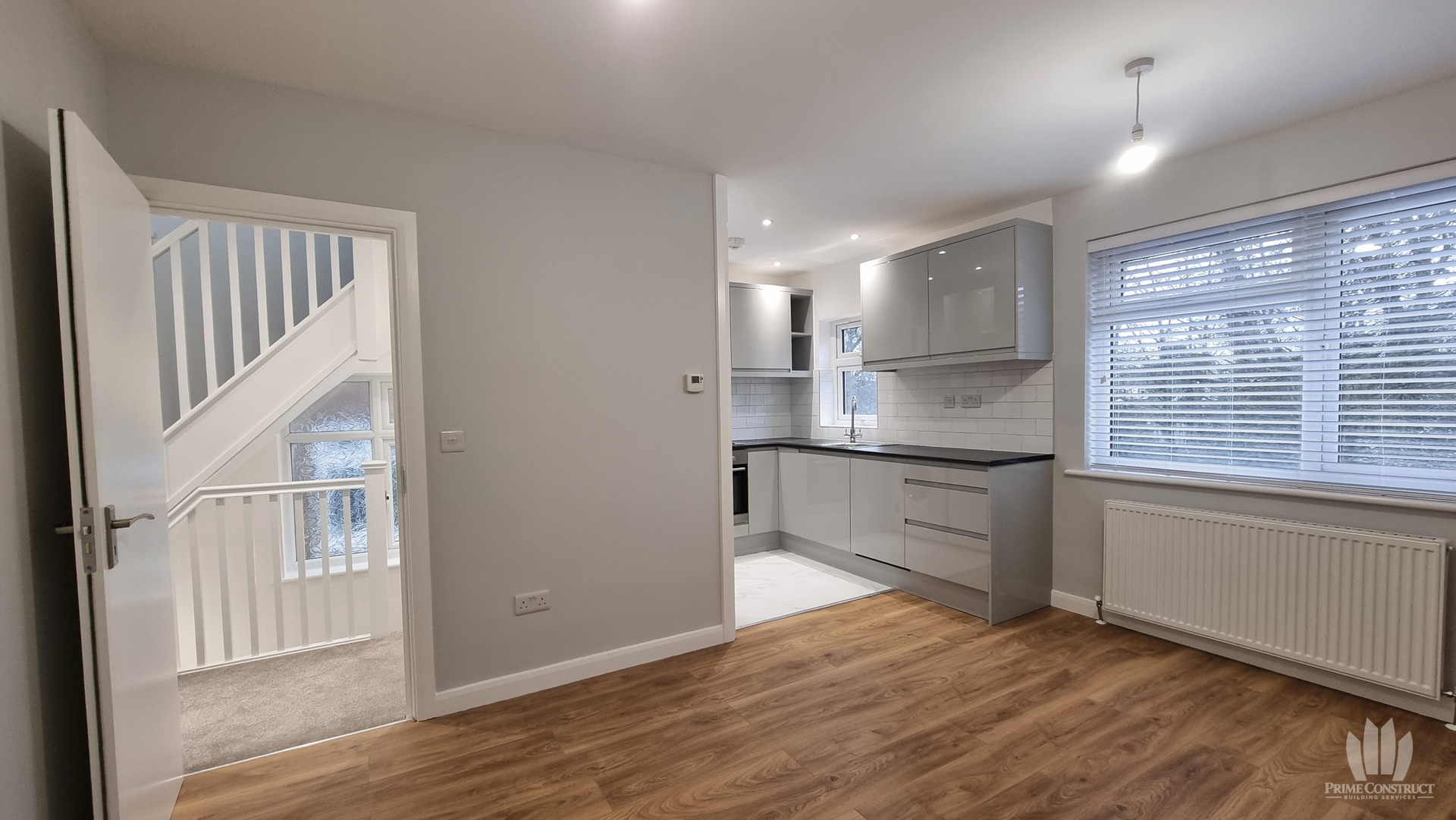 Grey fitted kitchen and living space beside the stair landing.