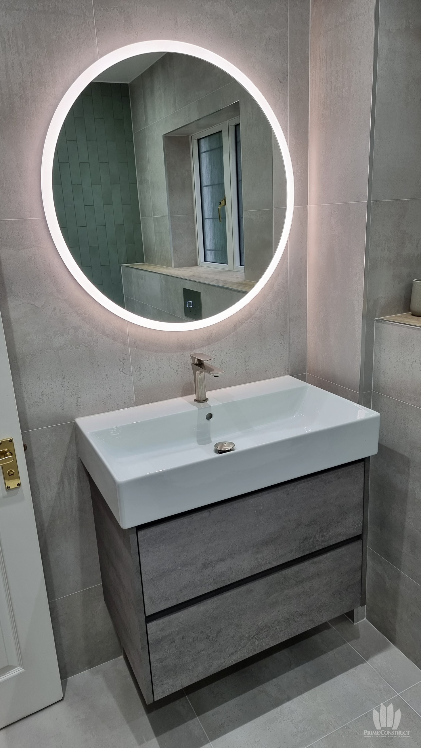 Master bathroom completed vanity and round illuminated mirror