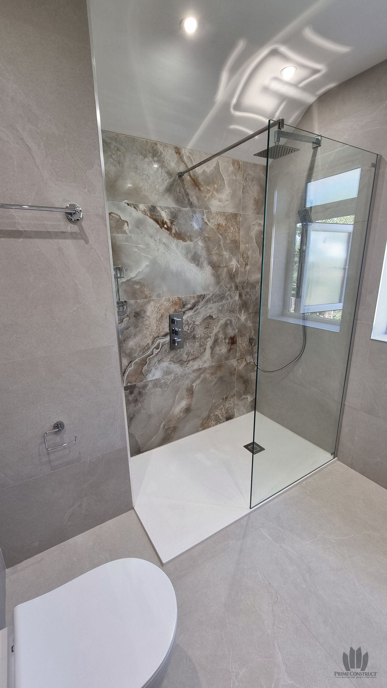 Completed shower with glass screen, feature tiling, overhead head and hand shower