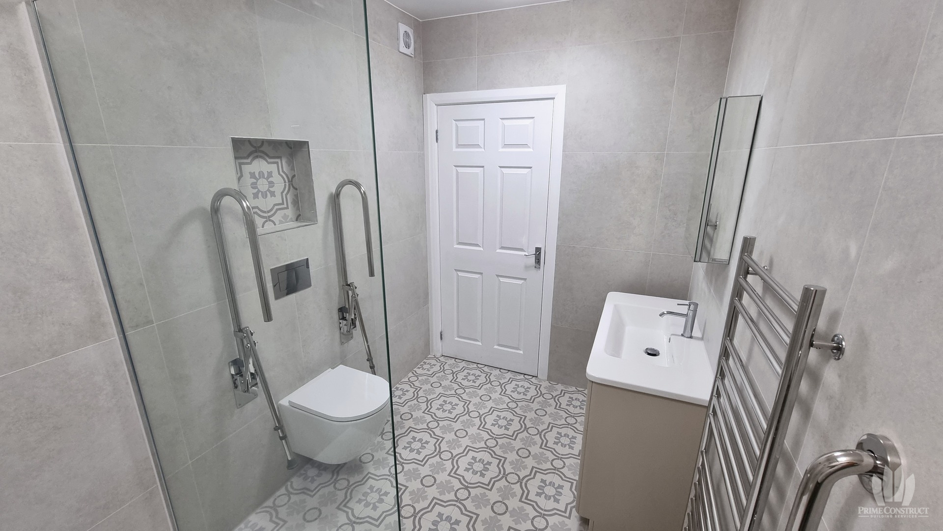 Reverse view from shower towards WC, door, vanity and towel rail.
