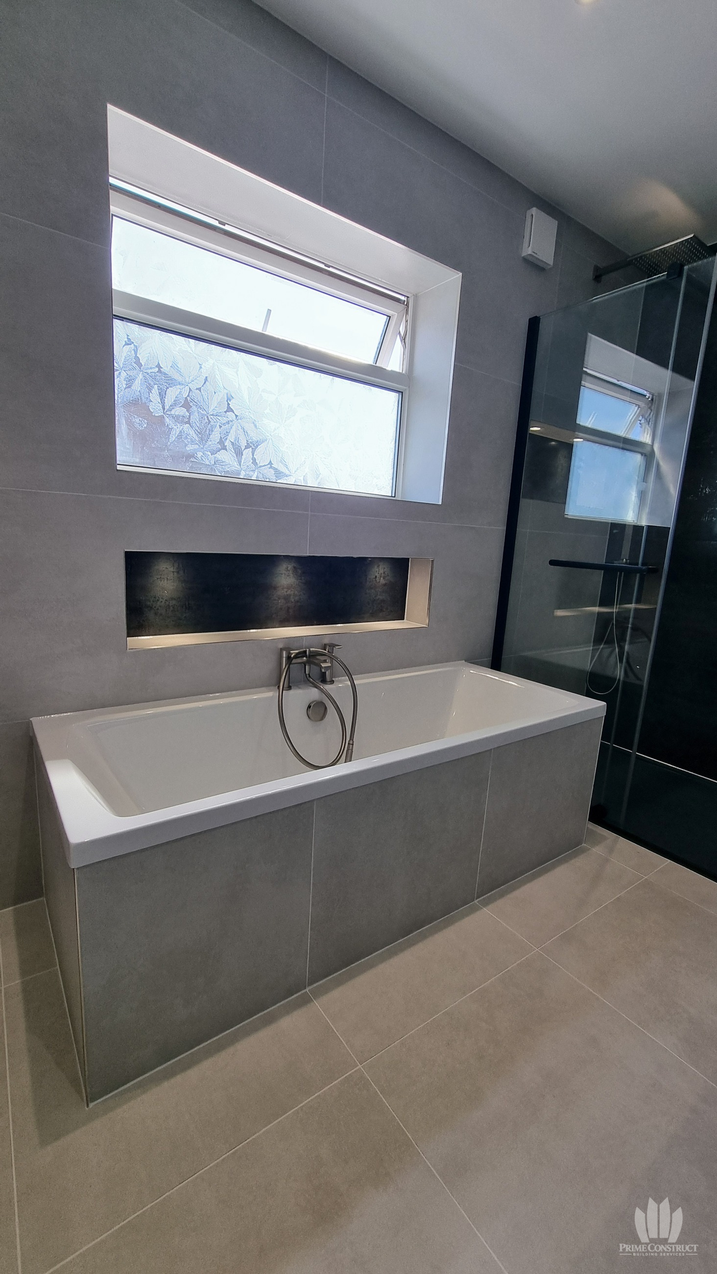 Bath below window with illuminated recess and shower edge.