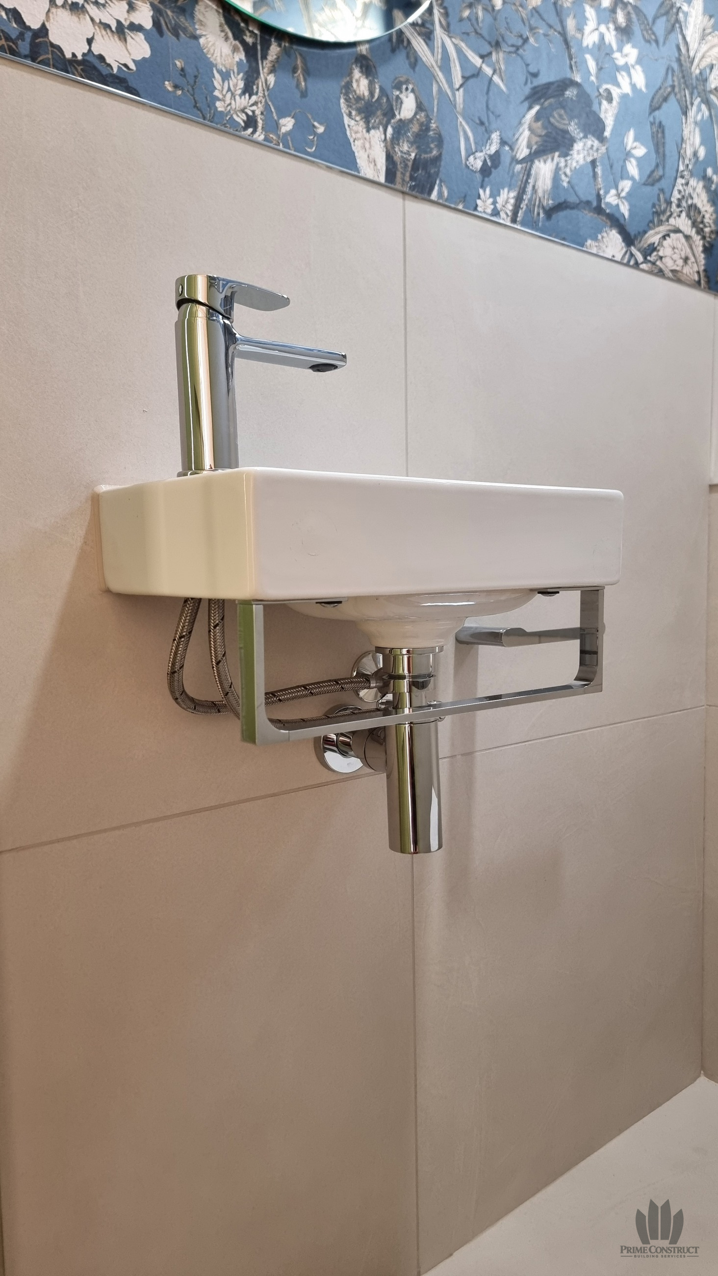 Small cloakroom basin and exposed chrome waste pipework.