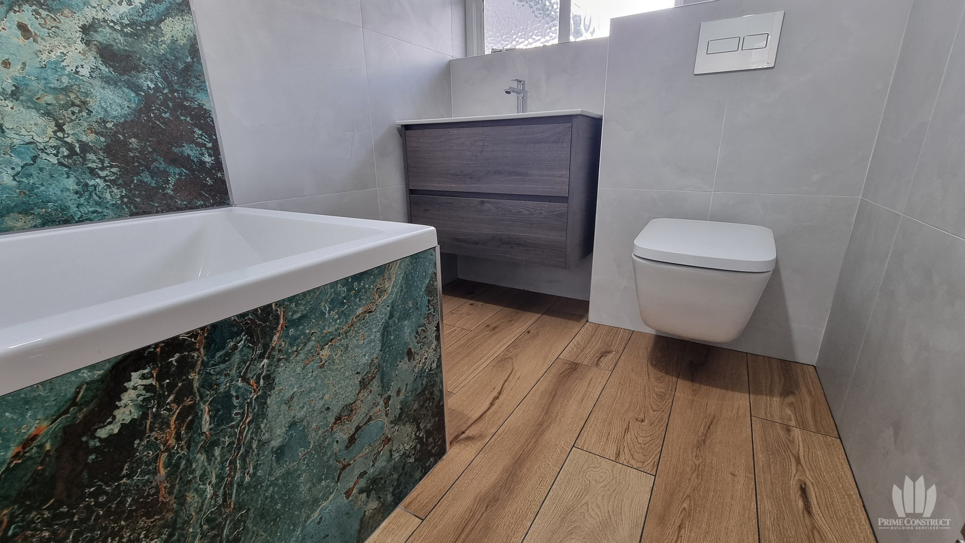 Finished bathroom with patterned teal feature tiles, timber-effect floor, vanity and WC.
