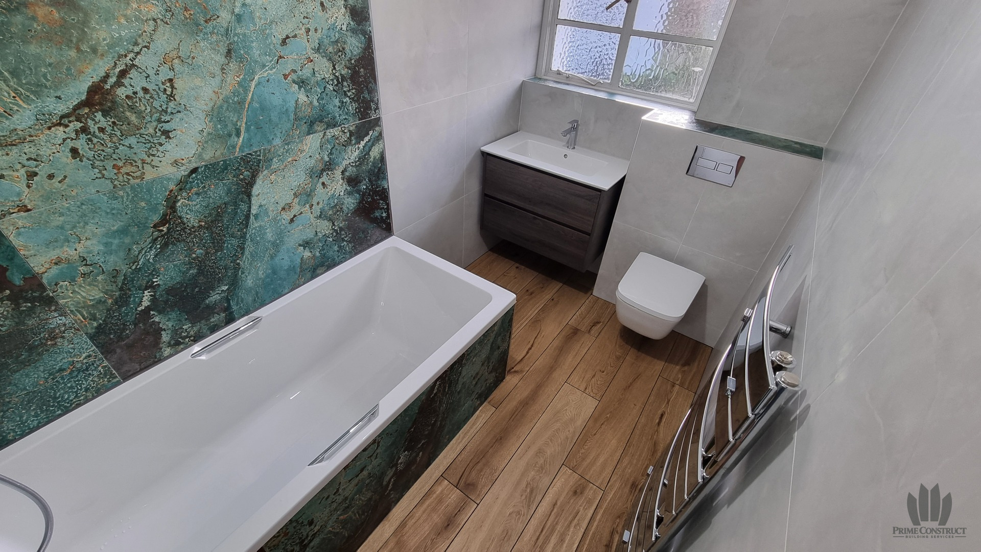 Finished bathroom with patterned teal feature tiles, timber-effect floor, vanity and WC.