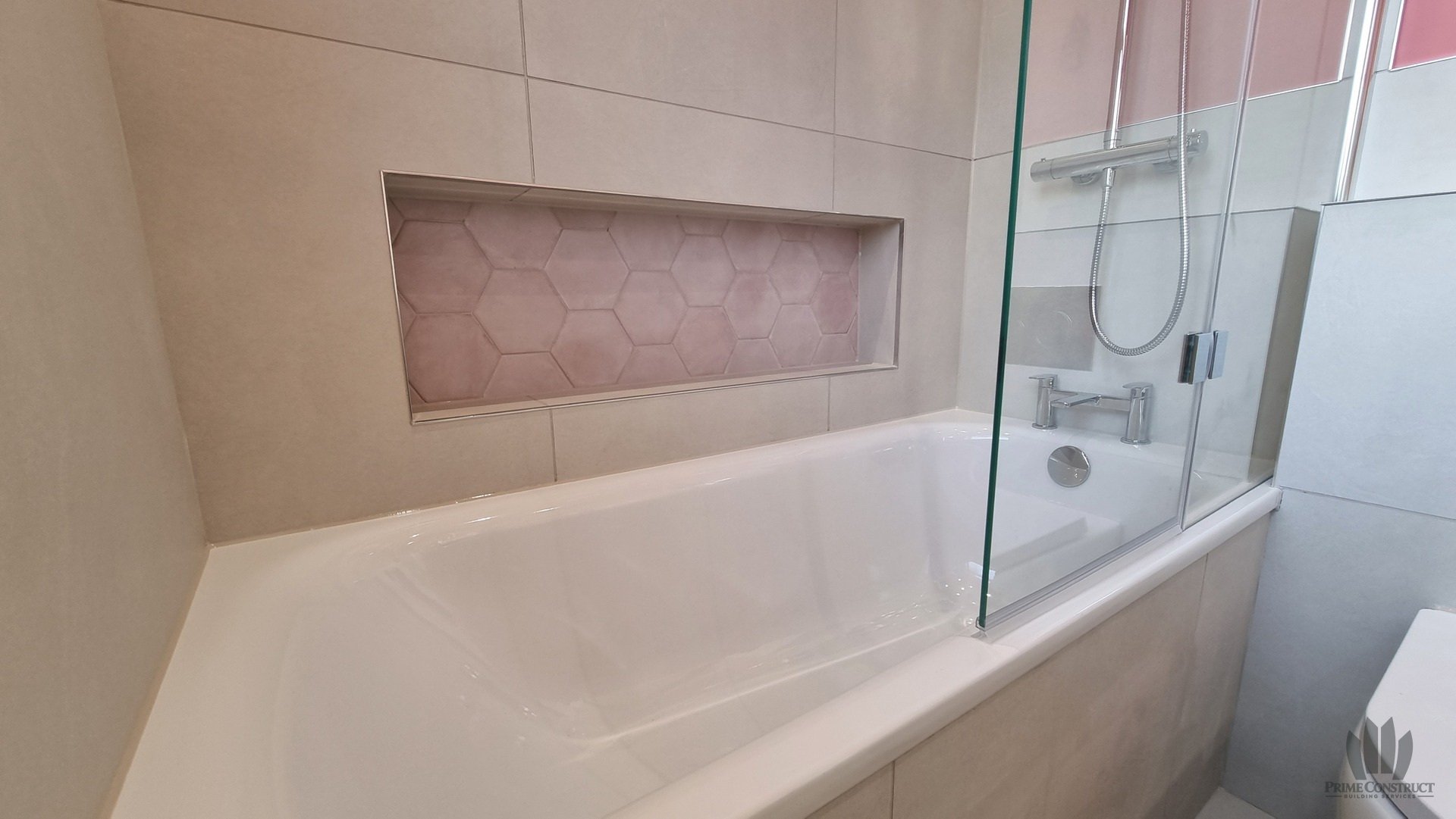 Pink bathroom bath, shower screen, recessed niche, concealed WC and tiling.