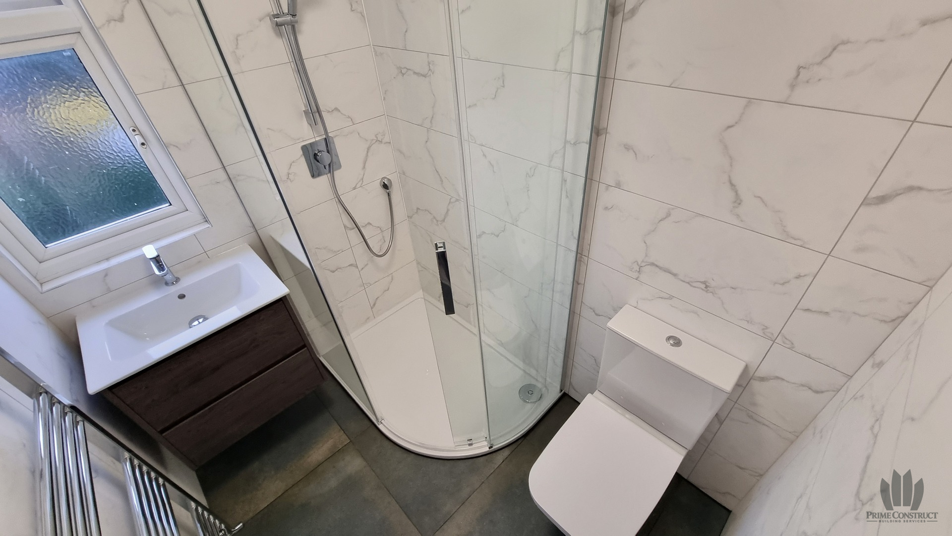 Compact shower room layout with curved enclosure, dark vanity and WC.